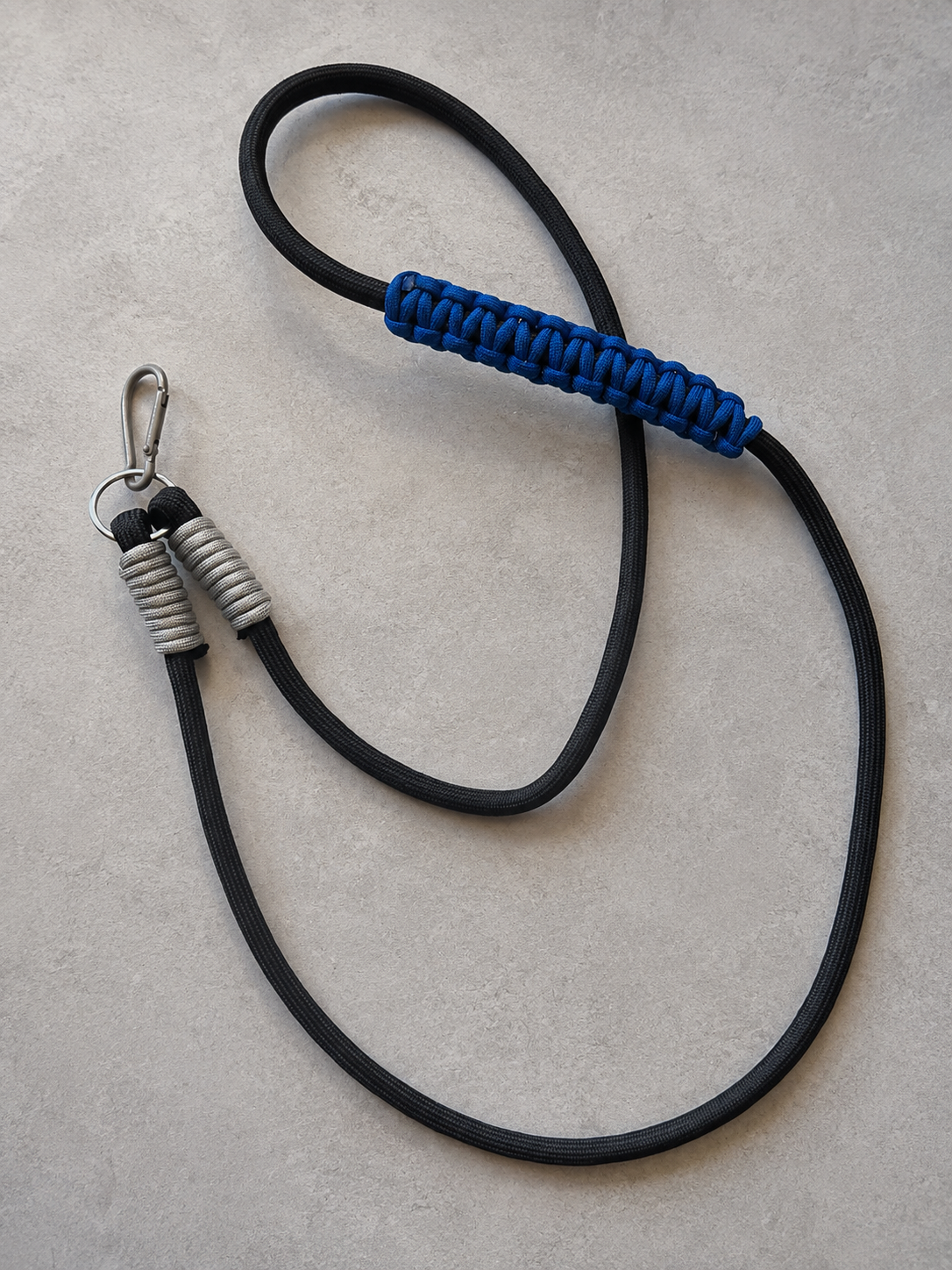 Czarno-niebieski phone strap crossbody midnight rave ułożony na jasnym kamiennym tle